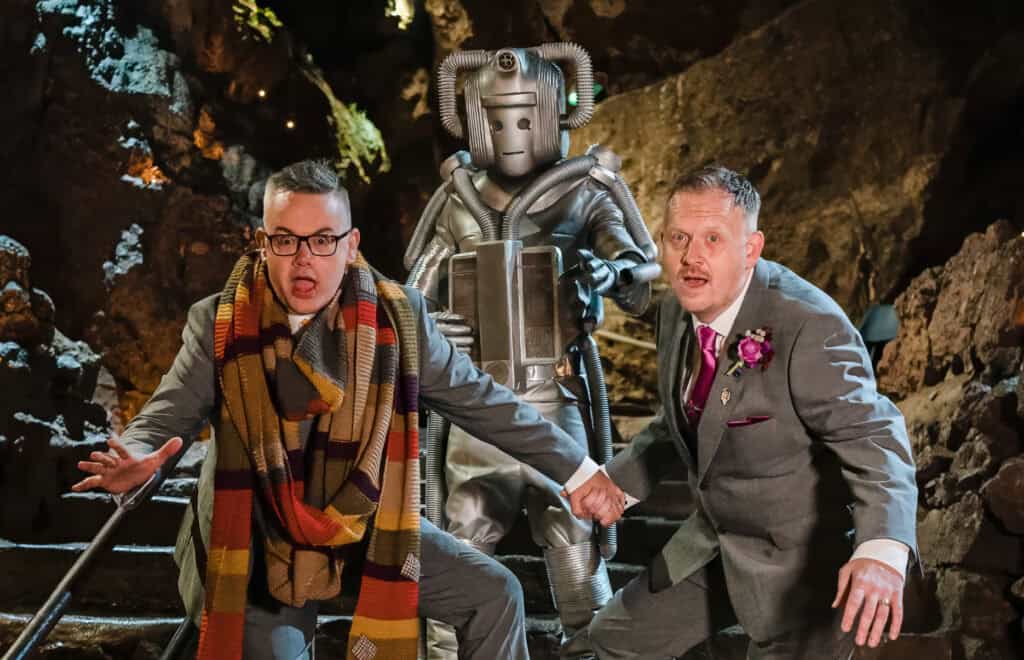 Modern couple with robot in cave setting, playful pose.