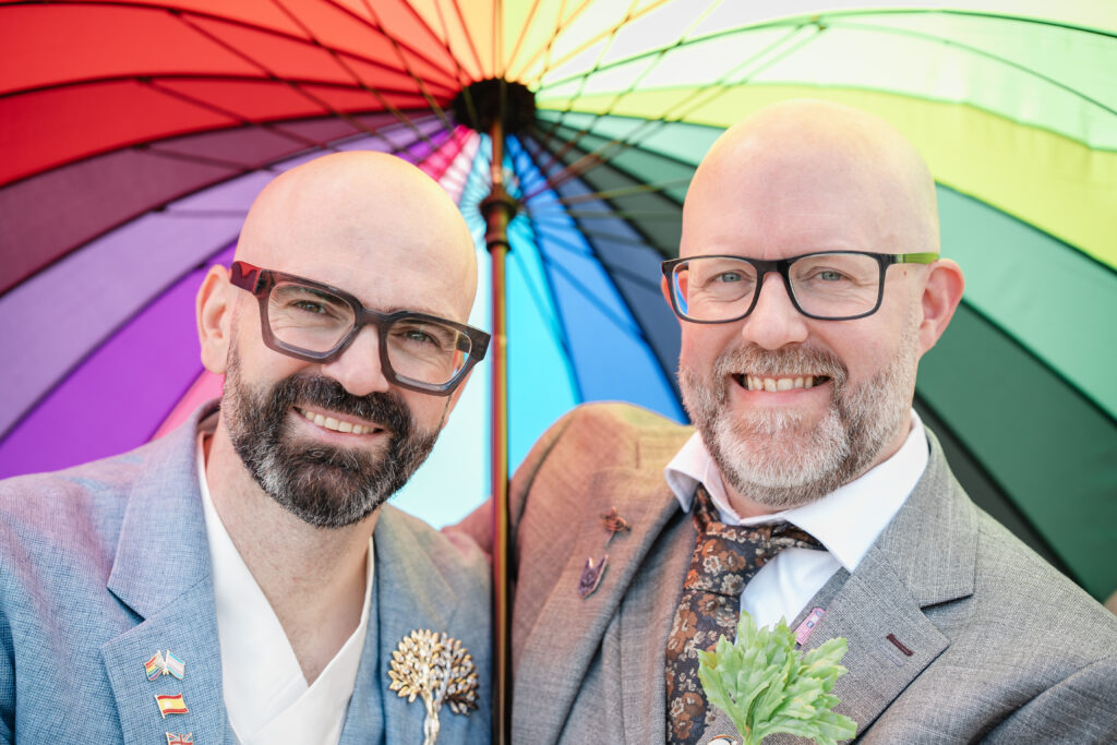 Dani and Stu under a rainbow umbrella