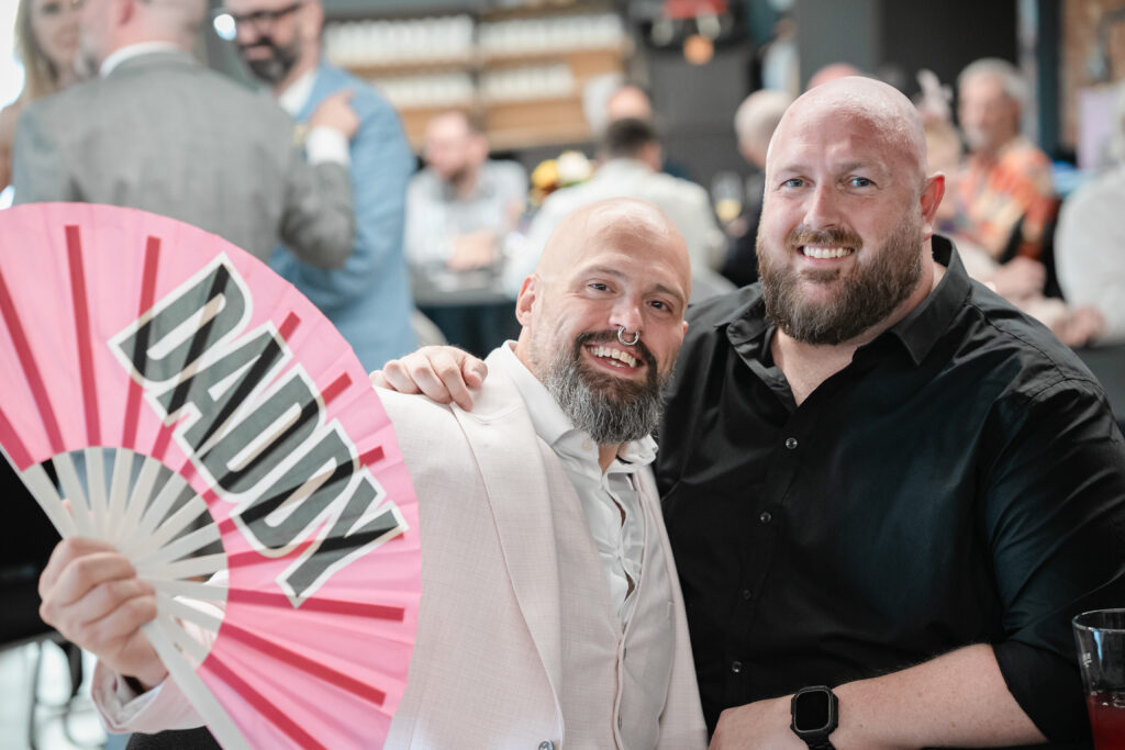 two gay bears and a fan that says Daddy