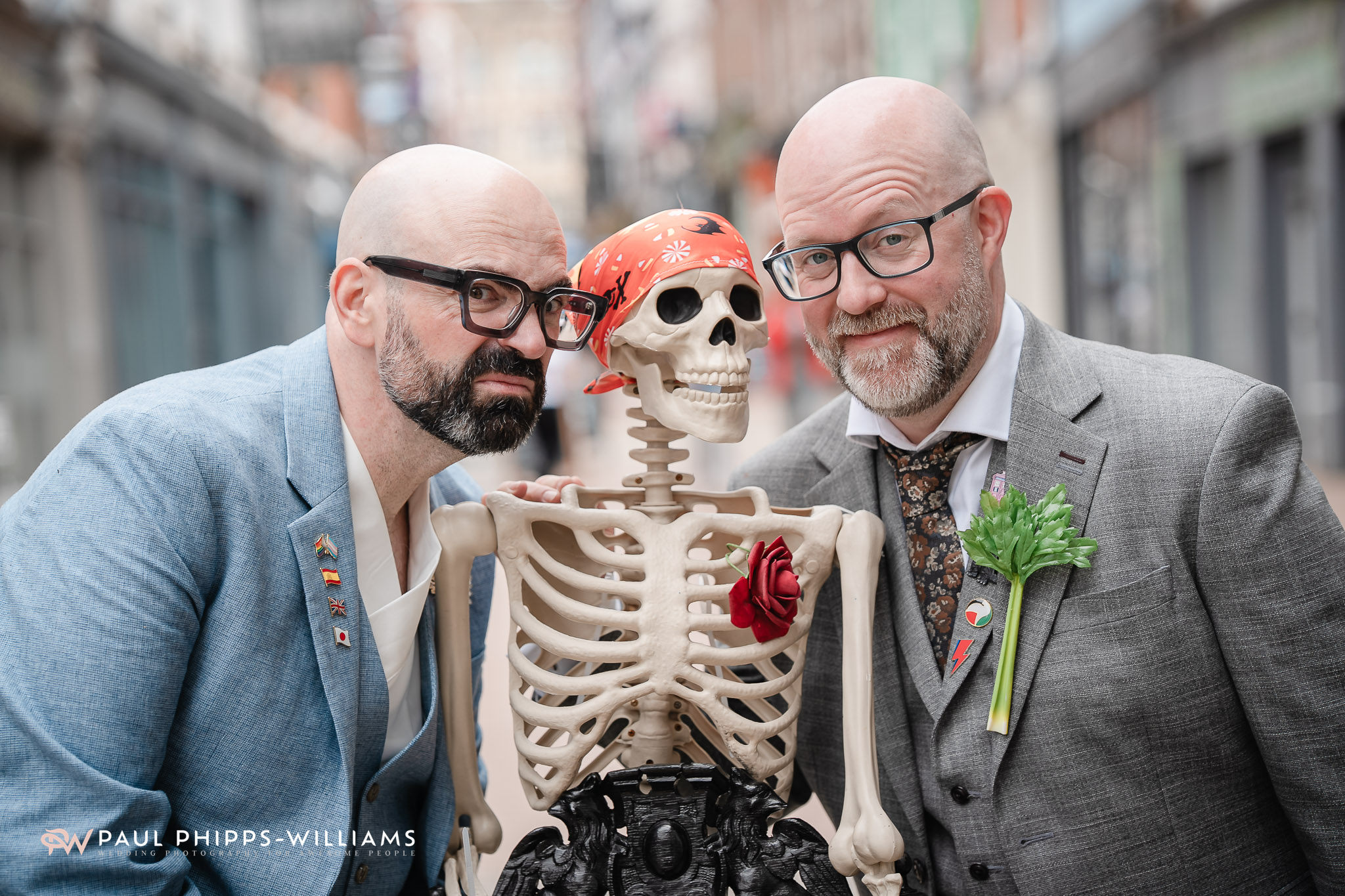 A same sex couple pull faces with a plastic skeleton