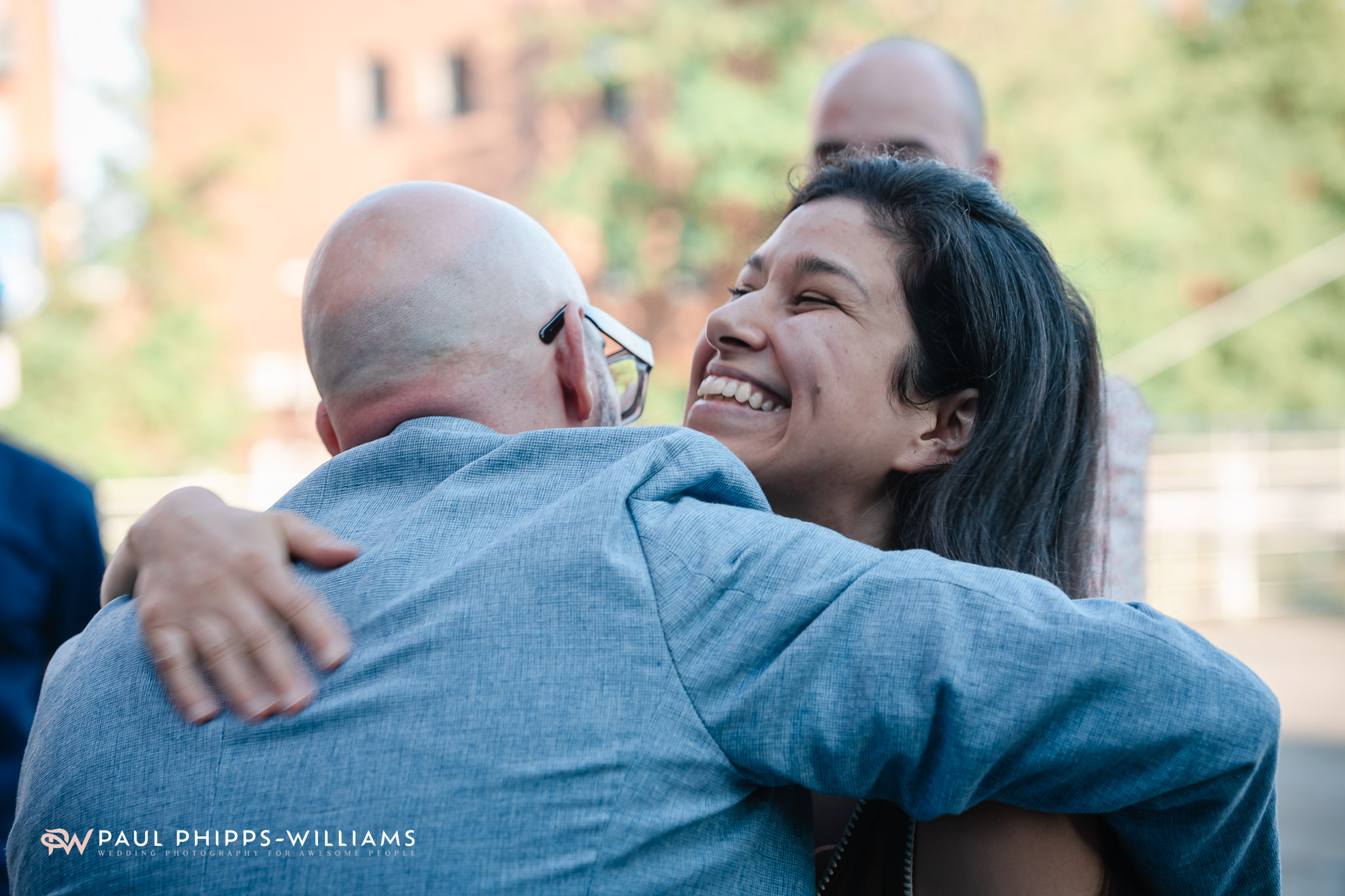 A wedding guest hugs a groom at the Museum of Making