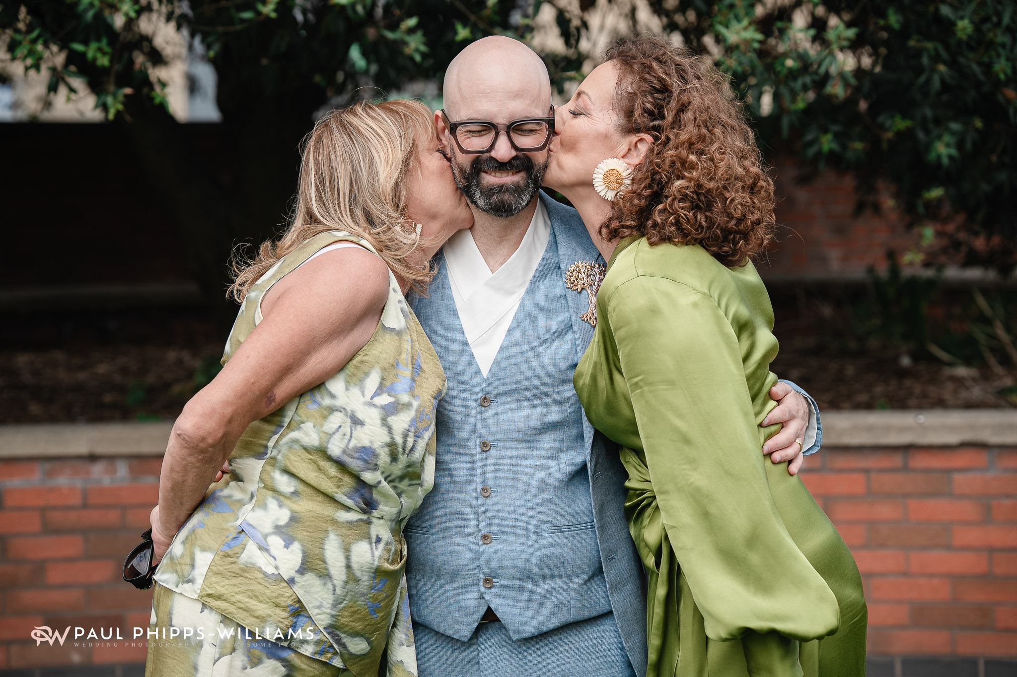 A groom's mum and sister kiss him on the cheeks