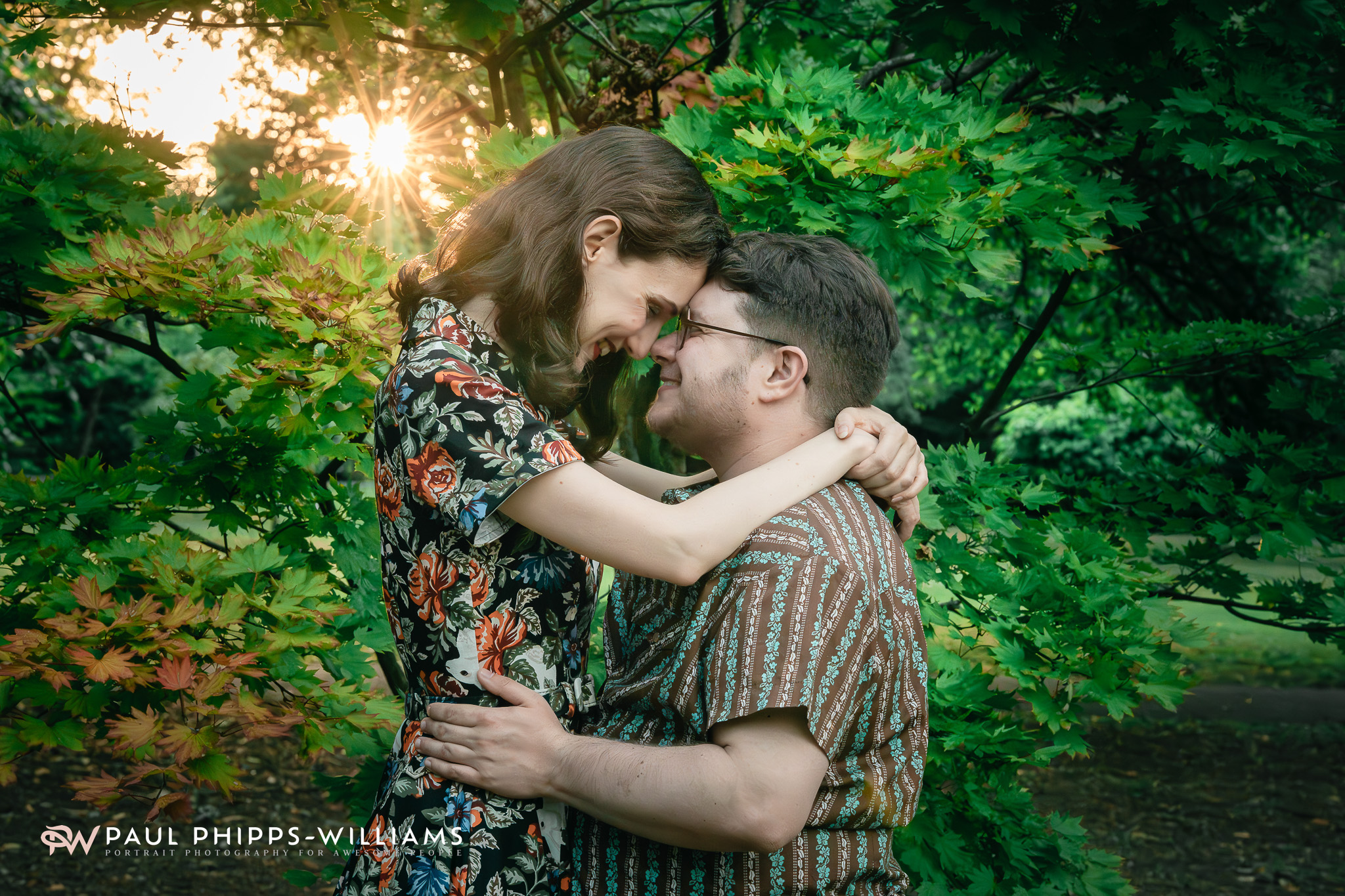 Anniversary portrait of Fio, a Manchester trans man, and Georgia framed by trees during a Manchester sunset