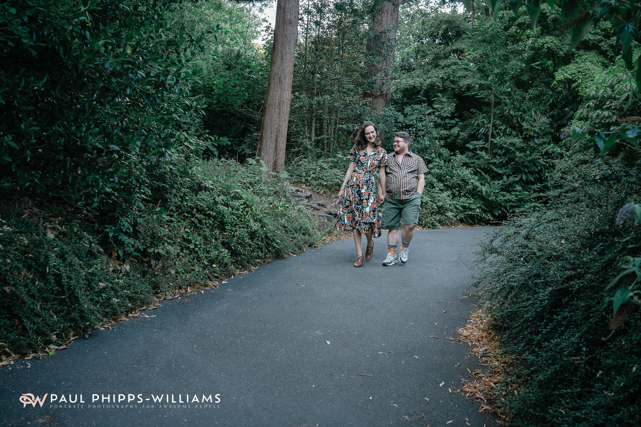 Fio and Georgia walking down a path in a Manchester Park for their anniversary portrait