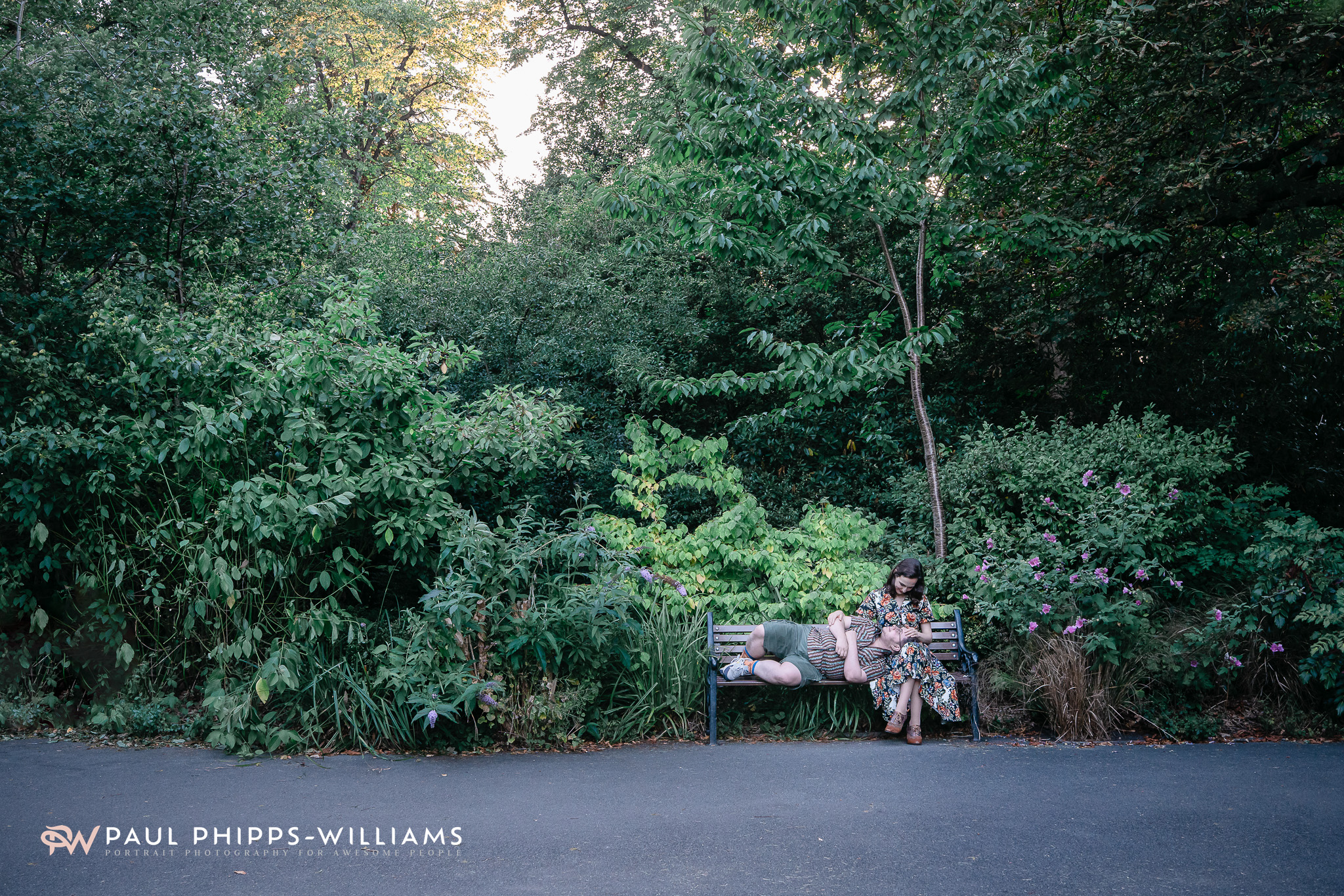 Long shot of Fio, a trans man from Manchester, lying in Georgia's arms on a bench