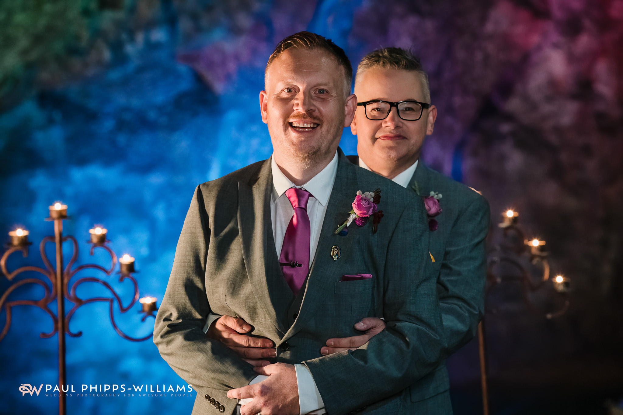 Andy and Dan hug at Wookey Hole whilst a blue light shines in the background.