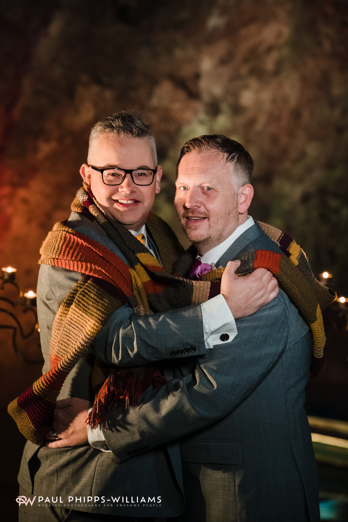 Andy and Dan embrace, wrapped in a Doctor Who scarf
