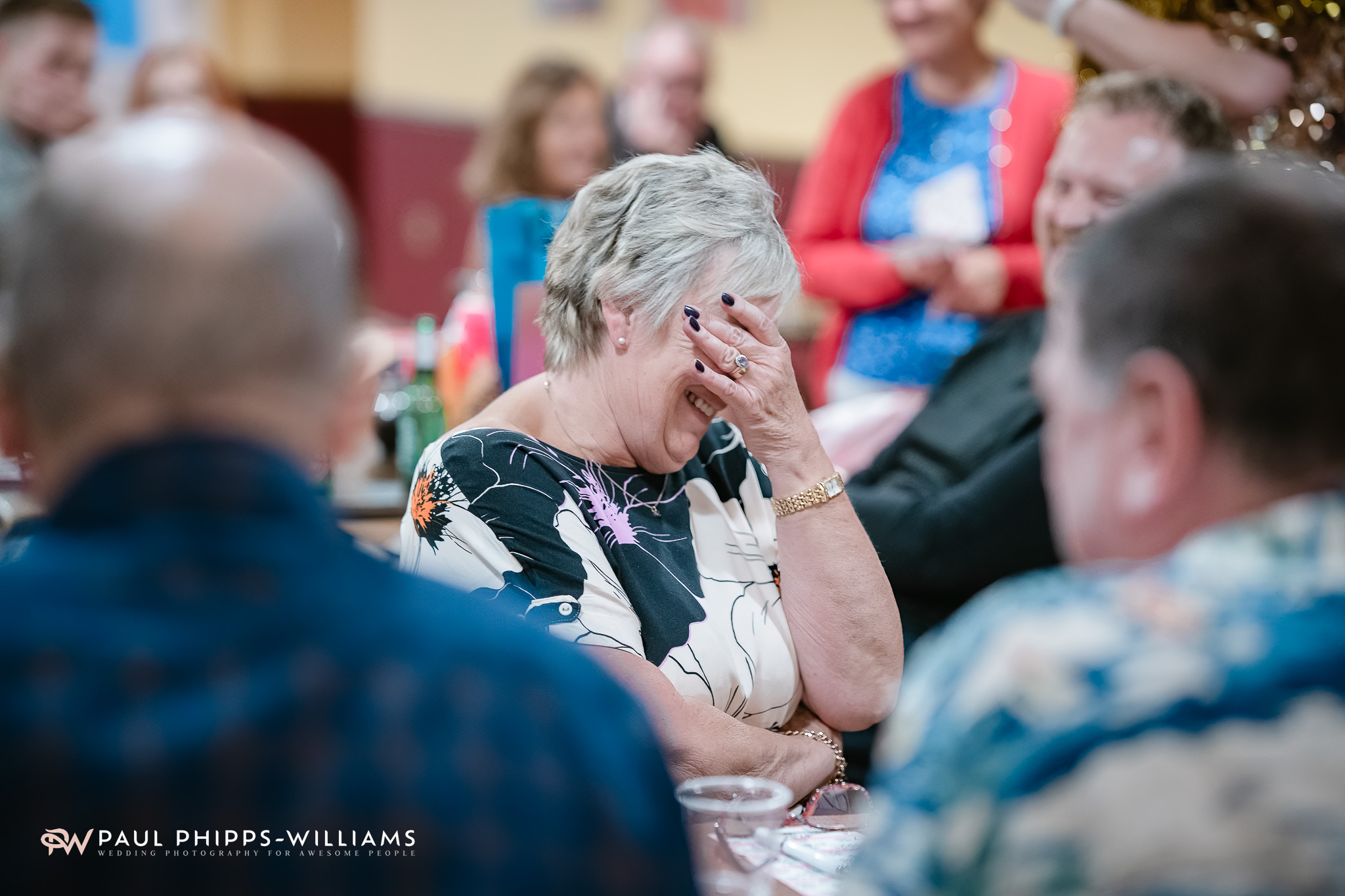 A wedding guest laughs into her hand