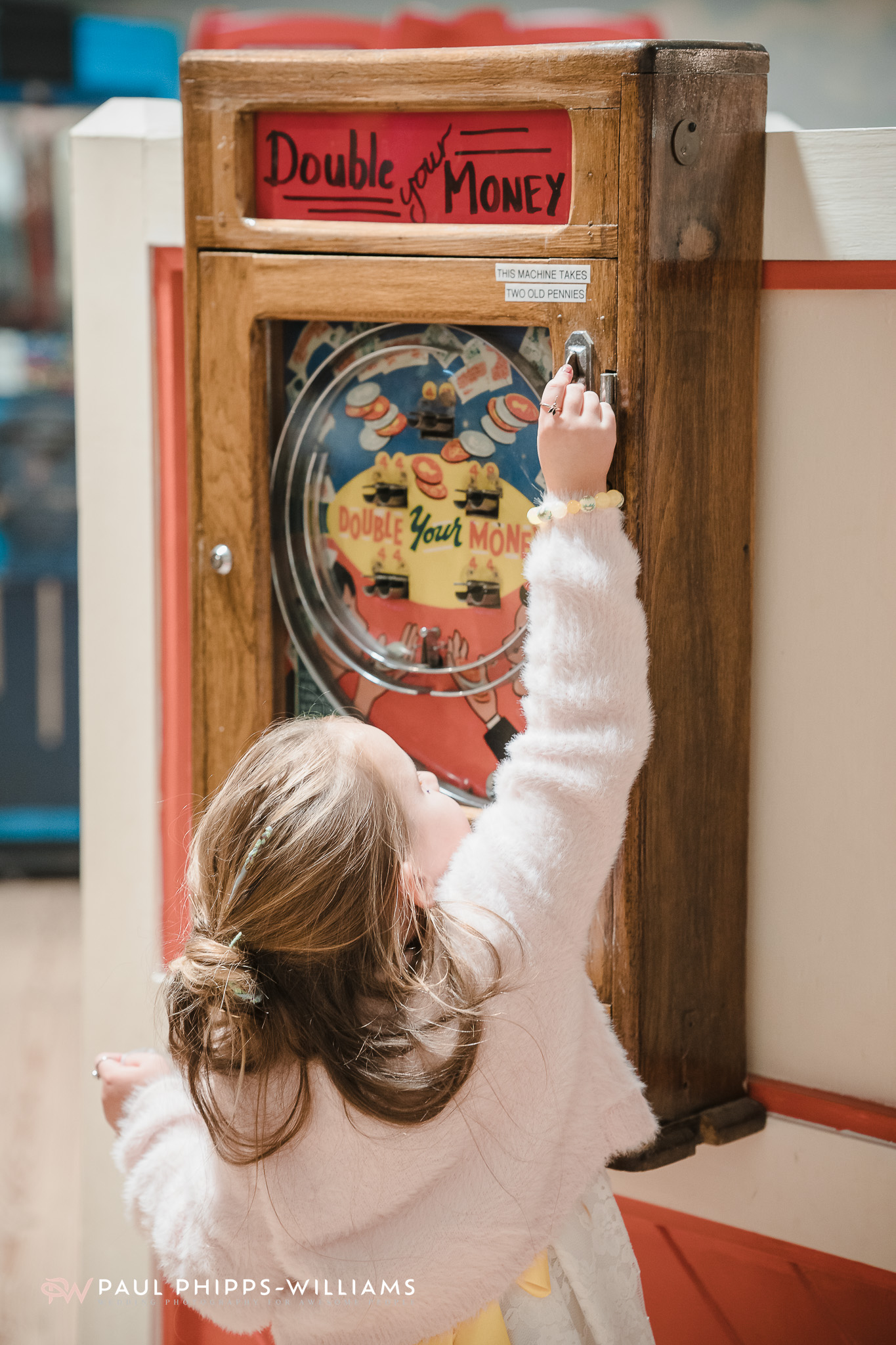 A child plays with a penny arcade machine during a wedding at Wookey Hole Caves