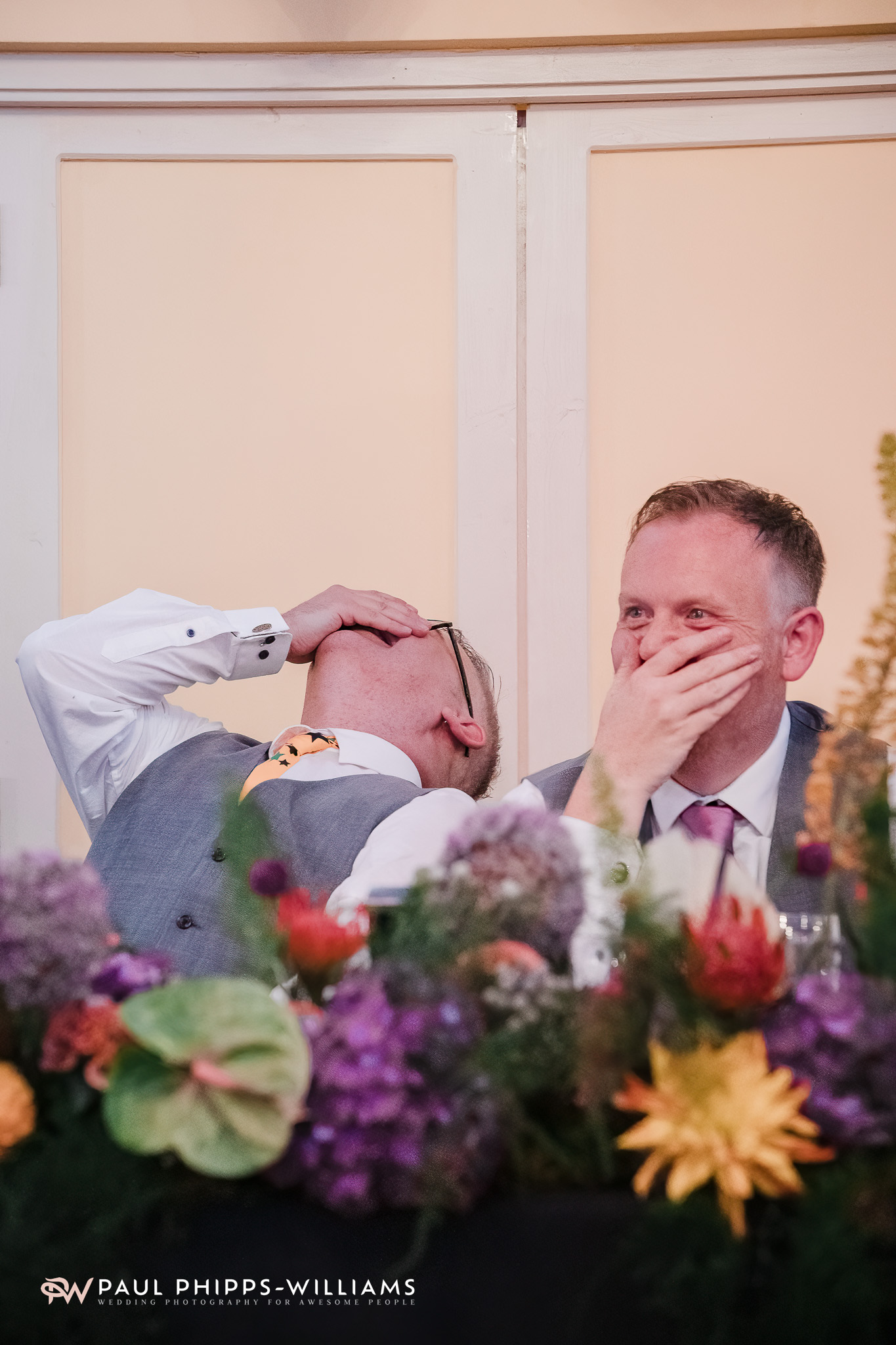 Andy and Dan laugh at a joke during speeches at their Wookey Hole wedding