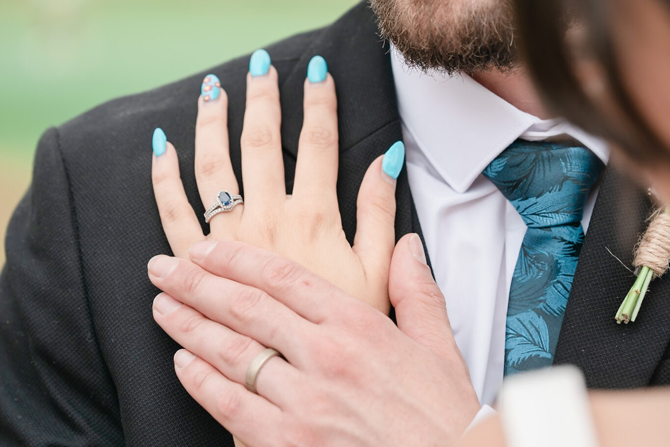 a bride wearing a wedding ring rests it on the shoulder of her groom.