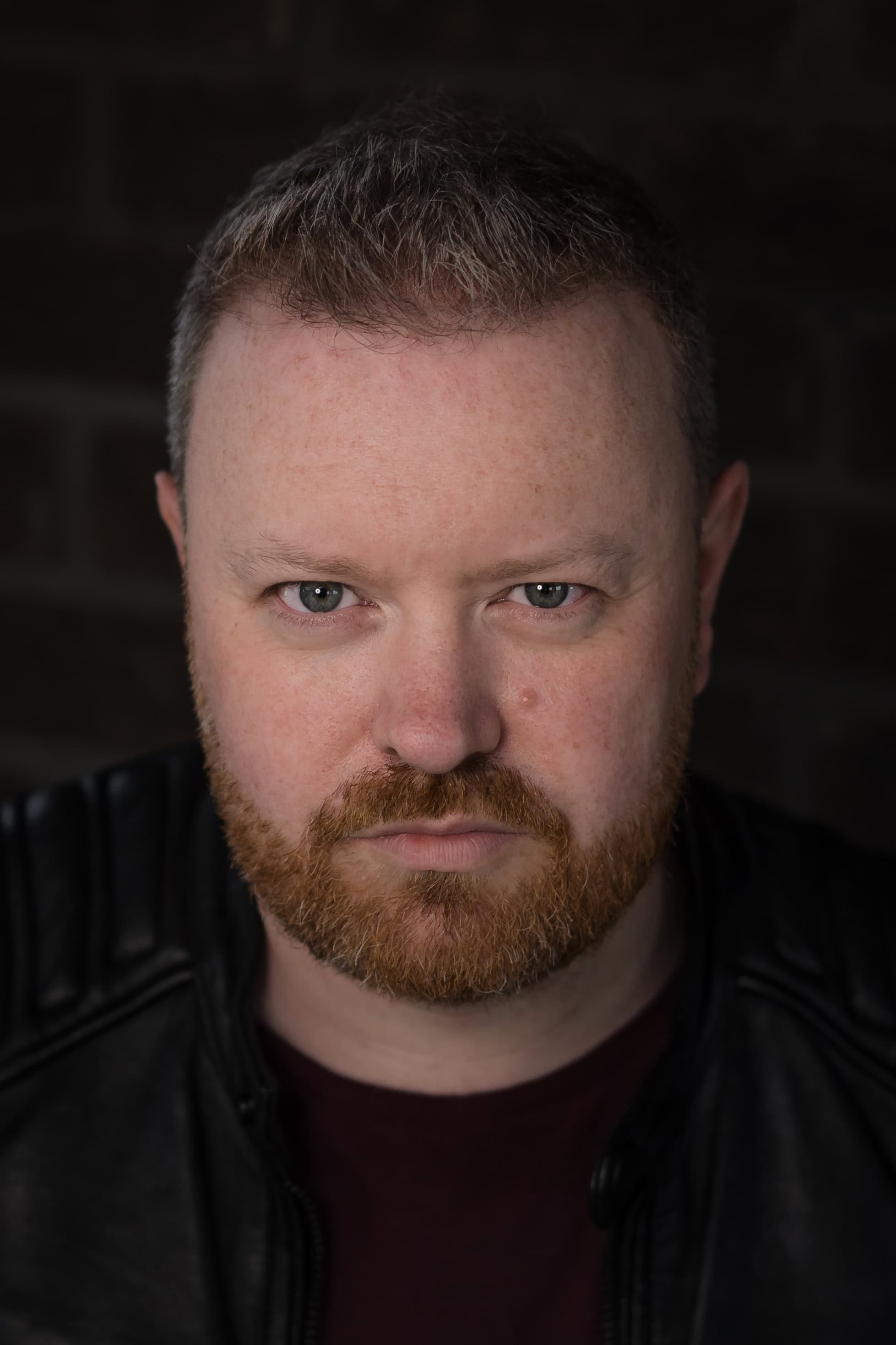 Portrait of Paul Phipps-Williams with intense gaze, studio lighting, dark background.