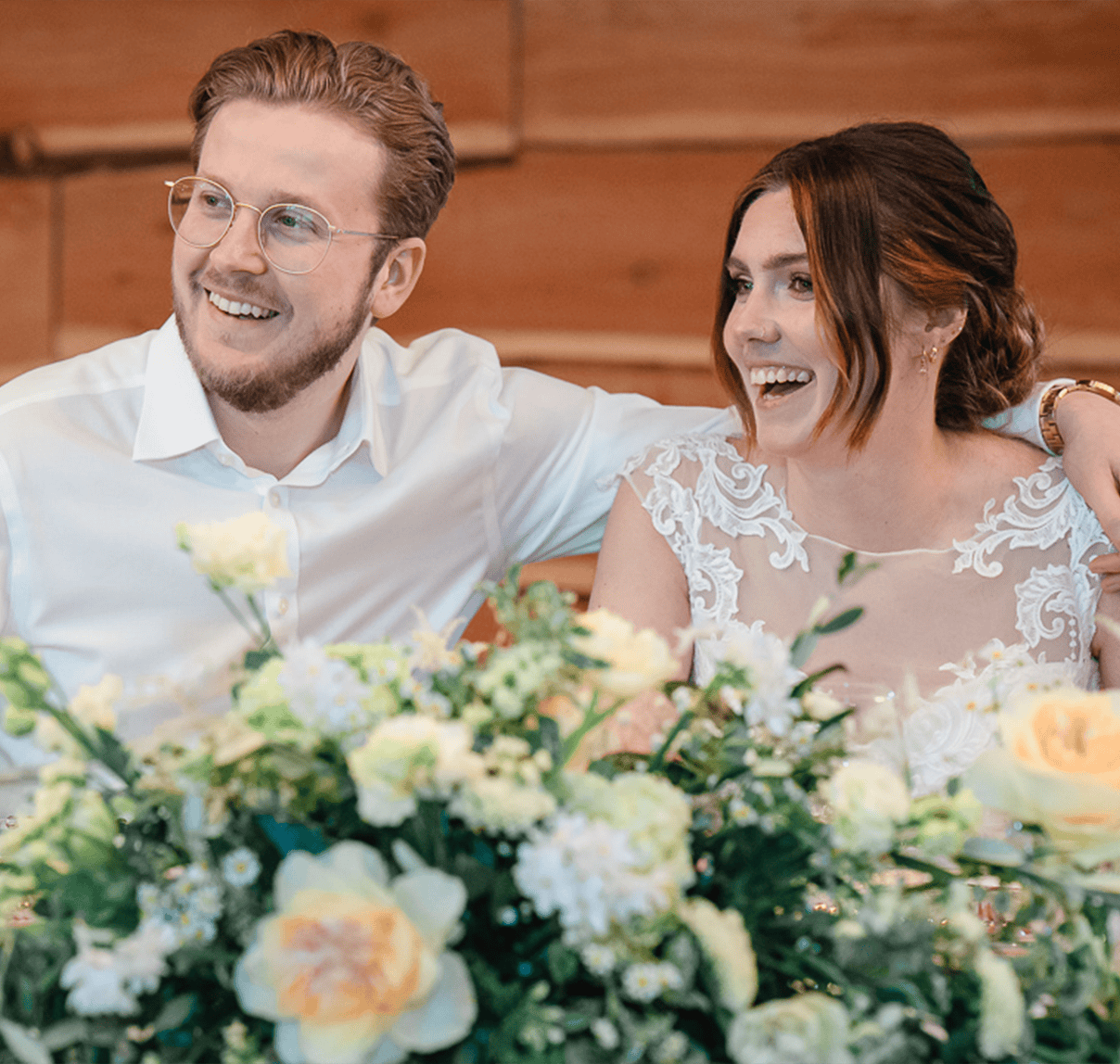Joyful wedding couple smiling with floral decor, captured by Paul Phipps-Williams Photography.