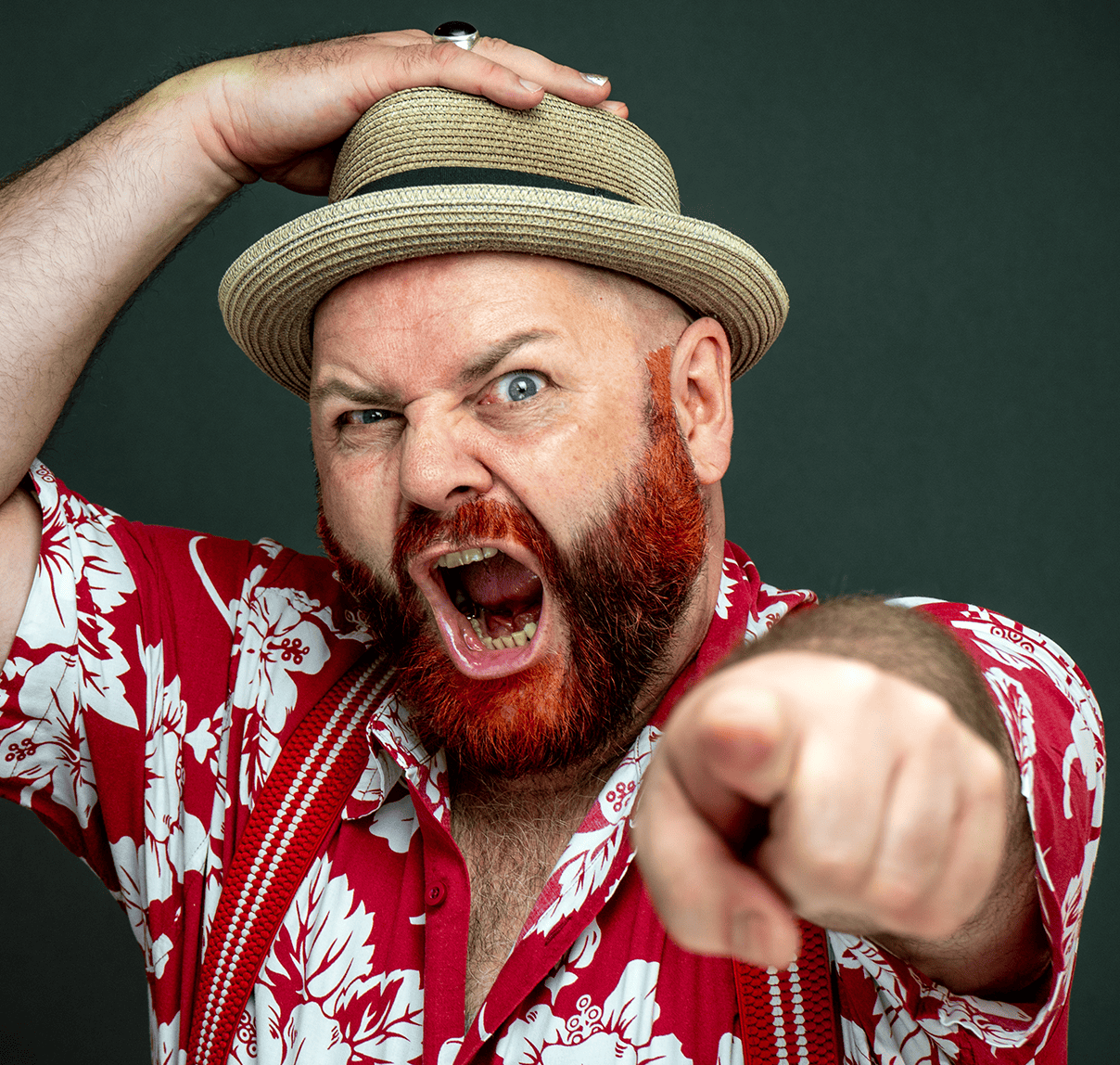 Man with a straw hat, red beard, and Hawaiian shirt, shouting and pointing at the camera.