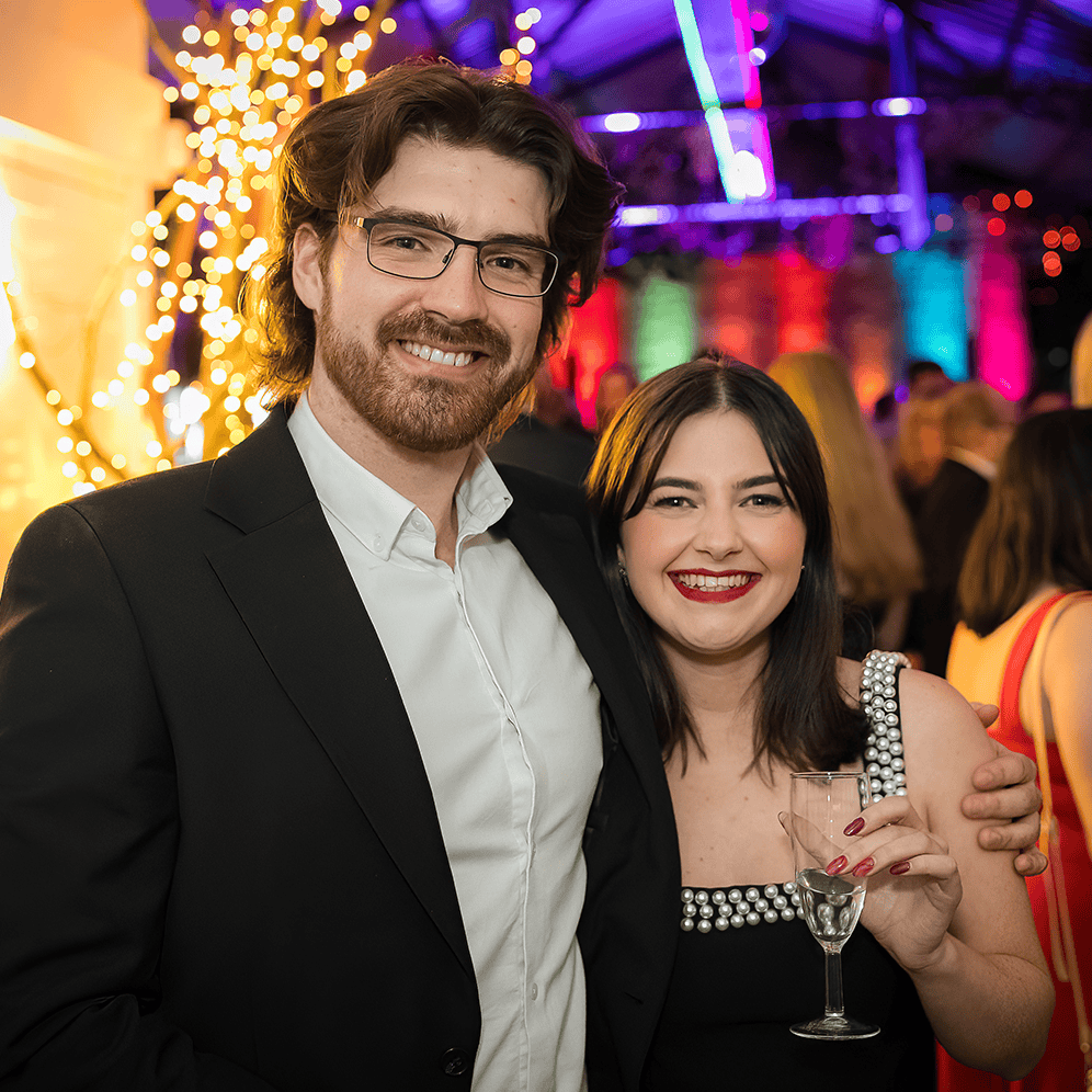 Celebrating at a vibrant event with colourful lights, featuring a smiling couple enjoying a night ou.