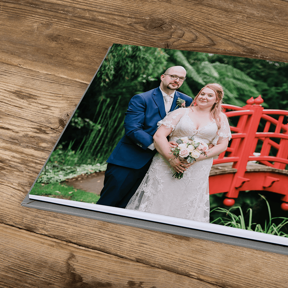 Wedding couple portrait in a lush garden with a red bridge, captured by Paul Phipps-Williams Photogr.