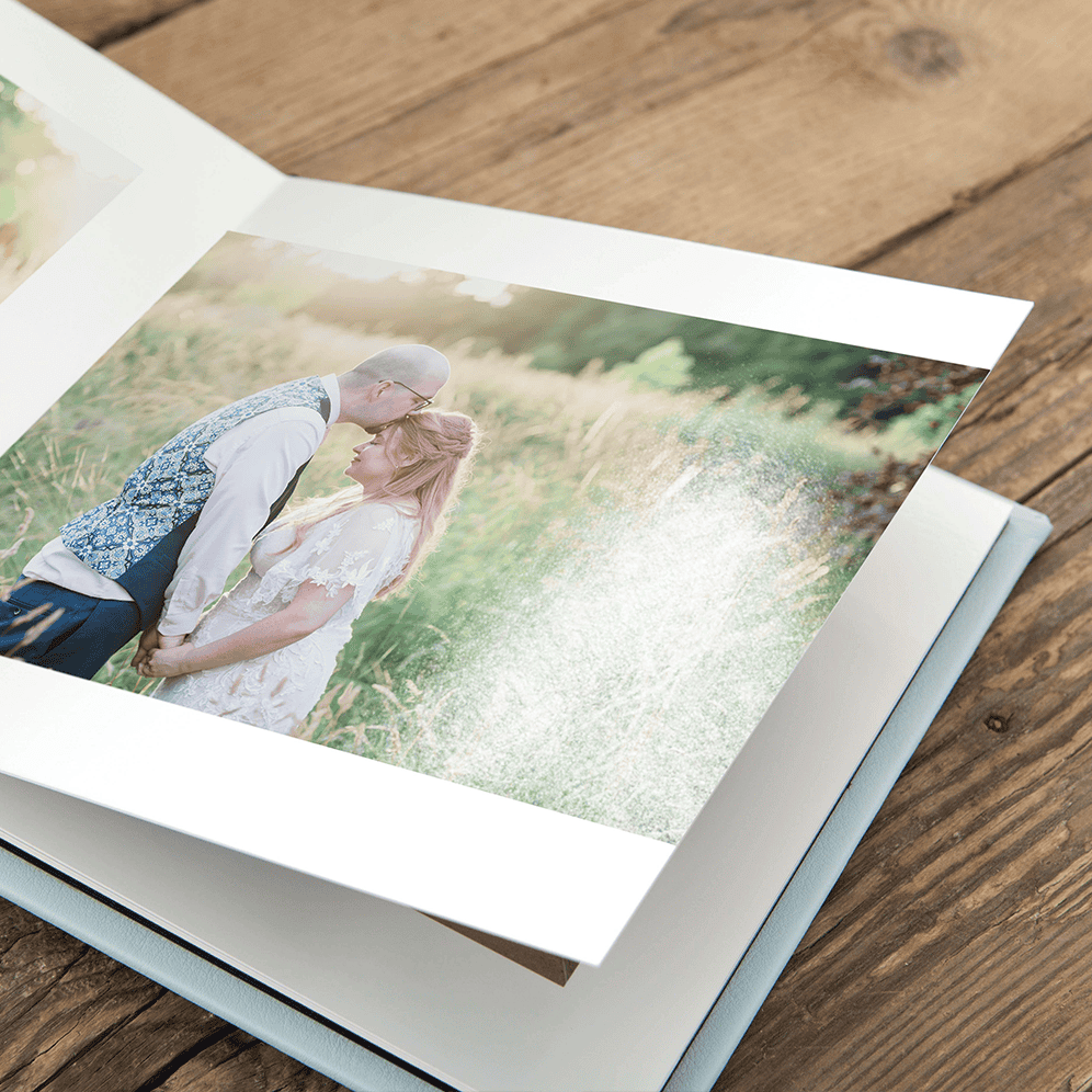 Romantic couple kissing outdoors in a lush green field, capturing love and intimacy in natural light.
