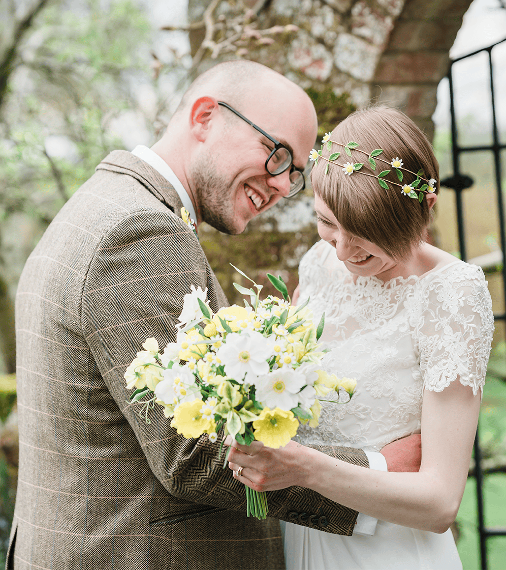 Wedding couple smiling with bouquet, outdoor wedding photography.