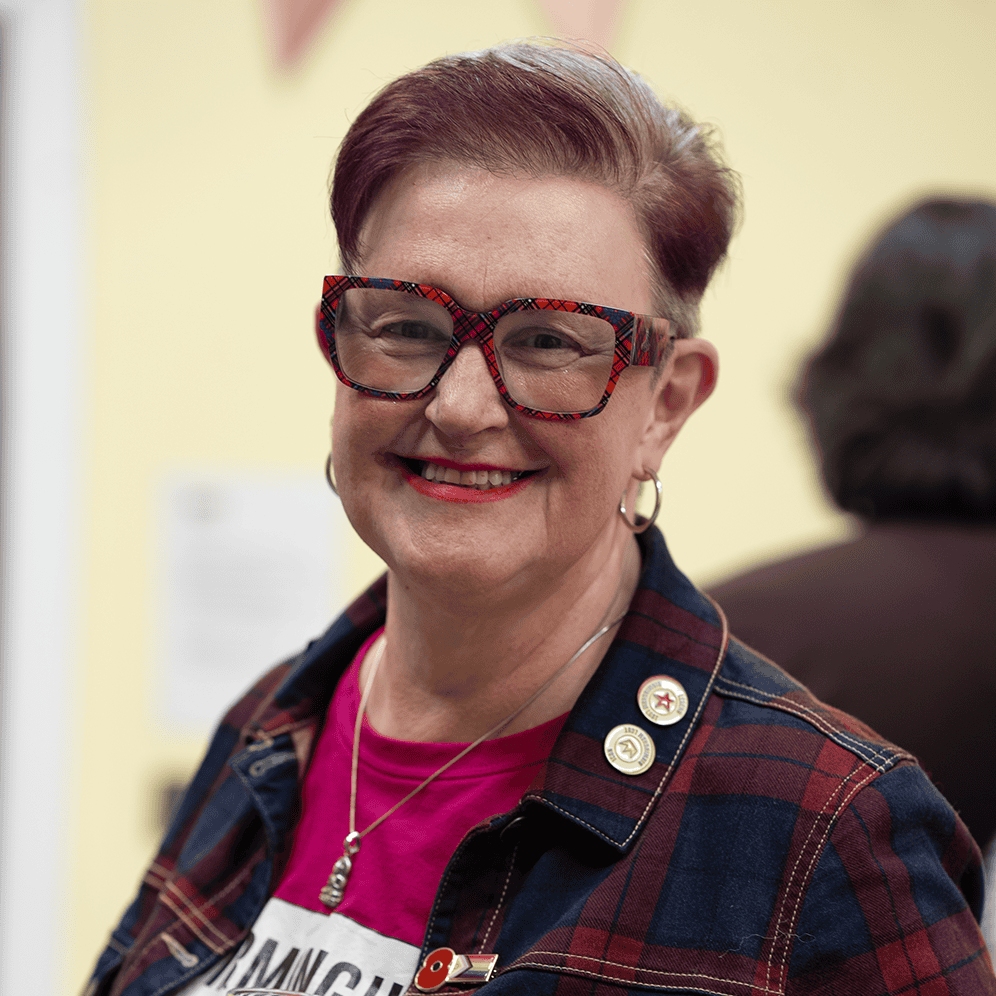 Vibrant portrait of a woman with short hair and colourful glasses, smiling warmly at a photography e.