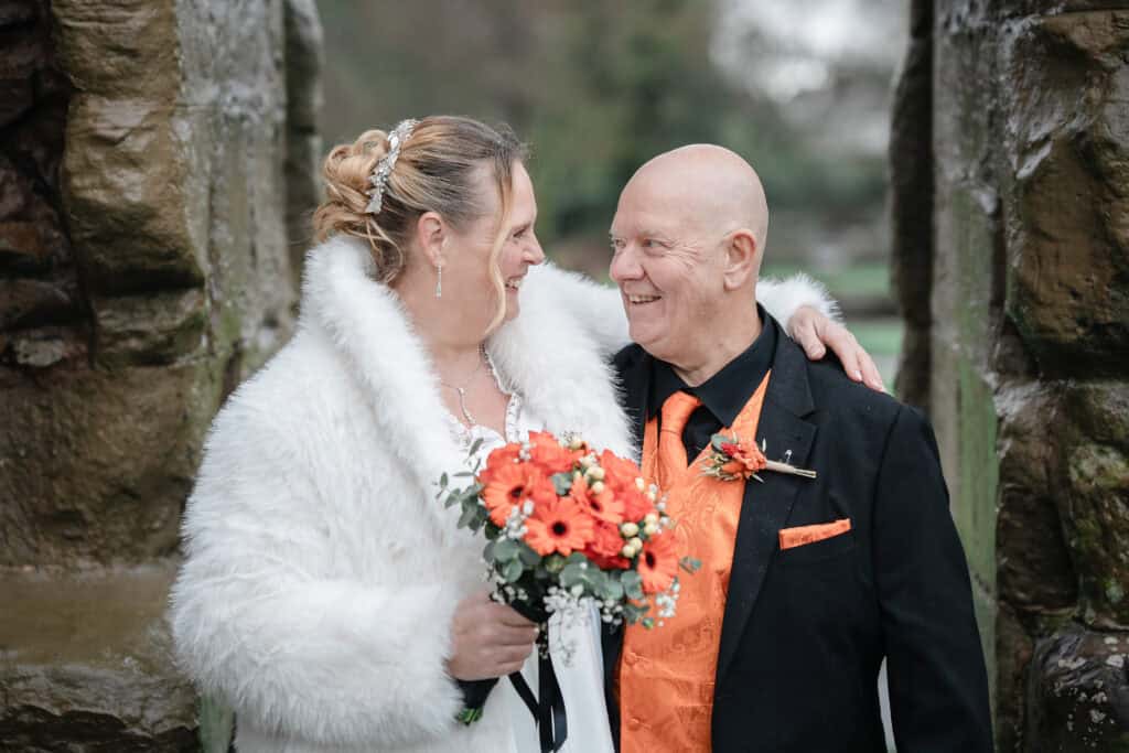 Wedding couple smiling and looking at each other, standing between stone formations in a scenic outd.