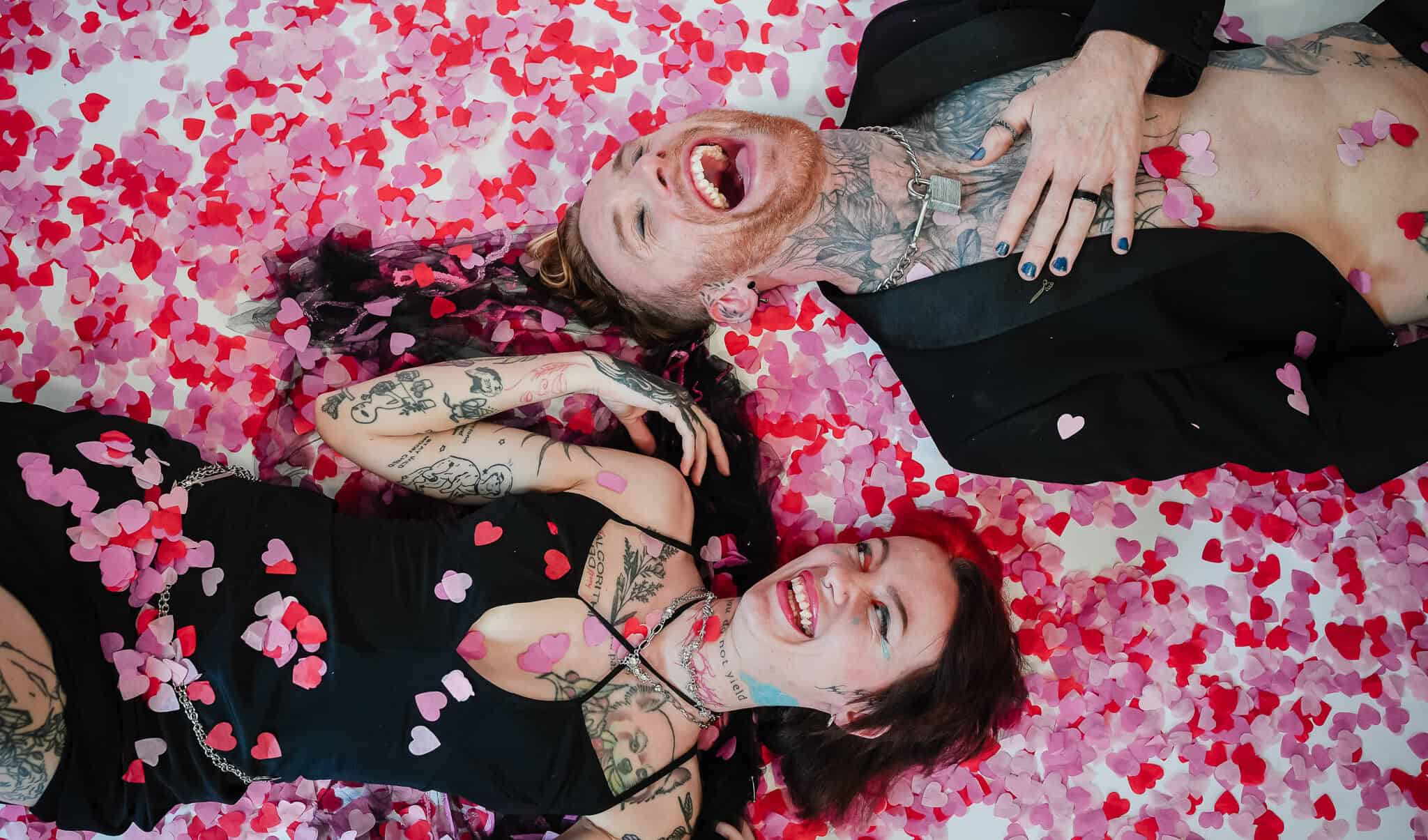 Portrait of two women lying on a bed of pink and red rose petals, smiling and enjoying the moment.