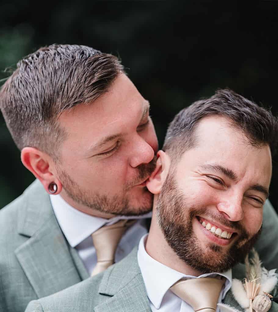 Happy gay couple smiling outdoors, celebrating love and connection.