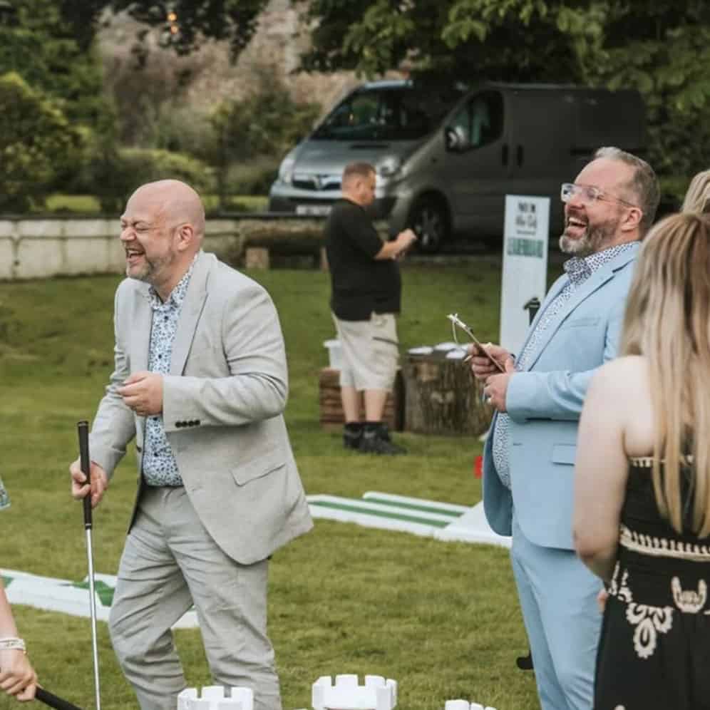 two people laugh in the garden whilst playing golf at a birmingham wedding