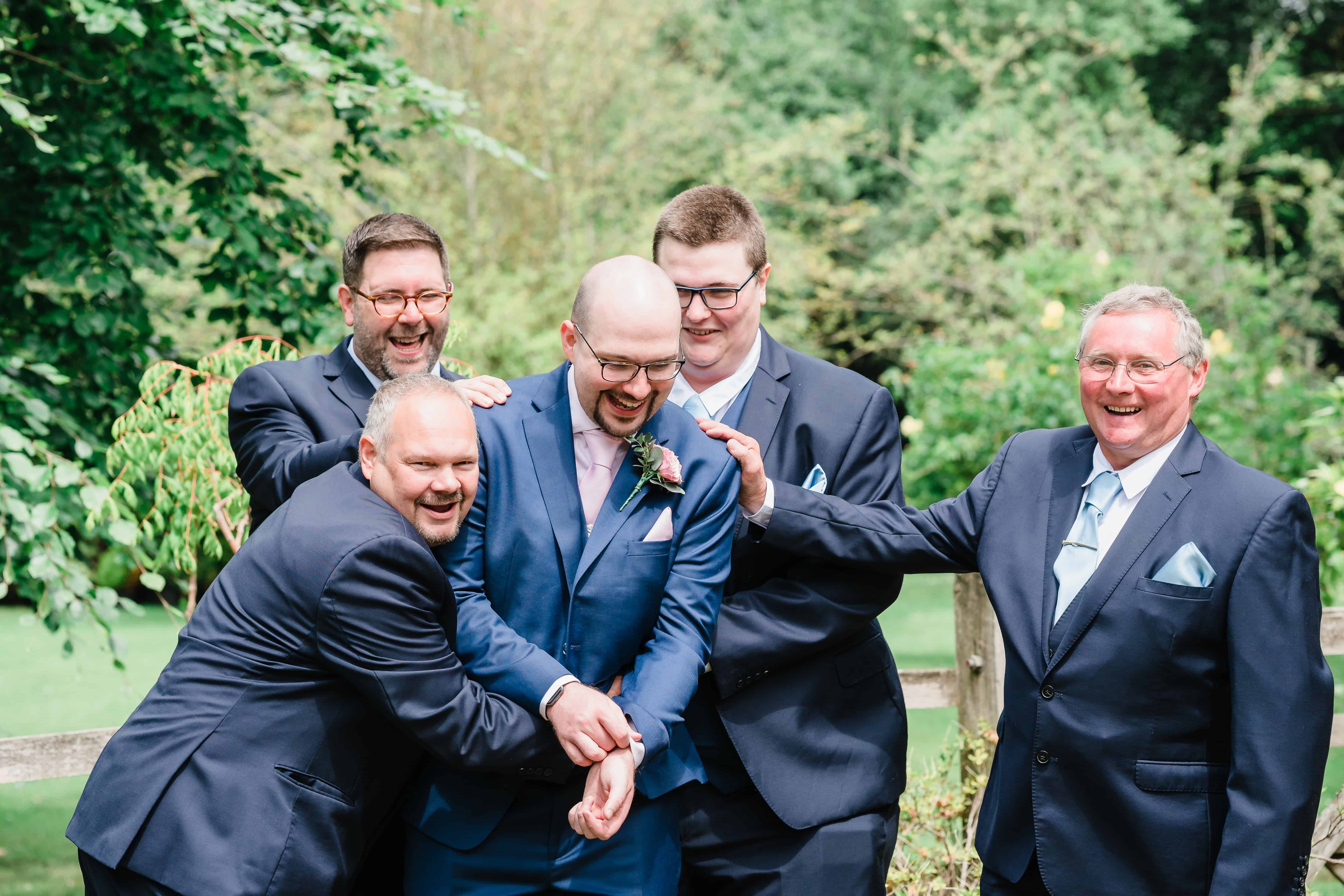 groomsmen laugh with a groom at his arrival at Rivervale barn