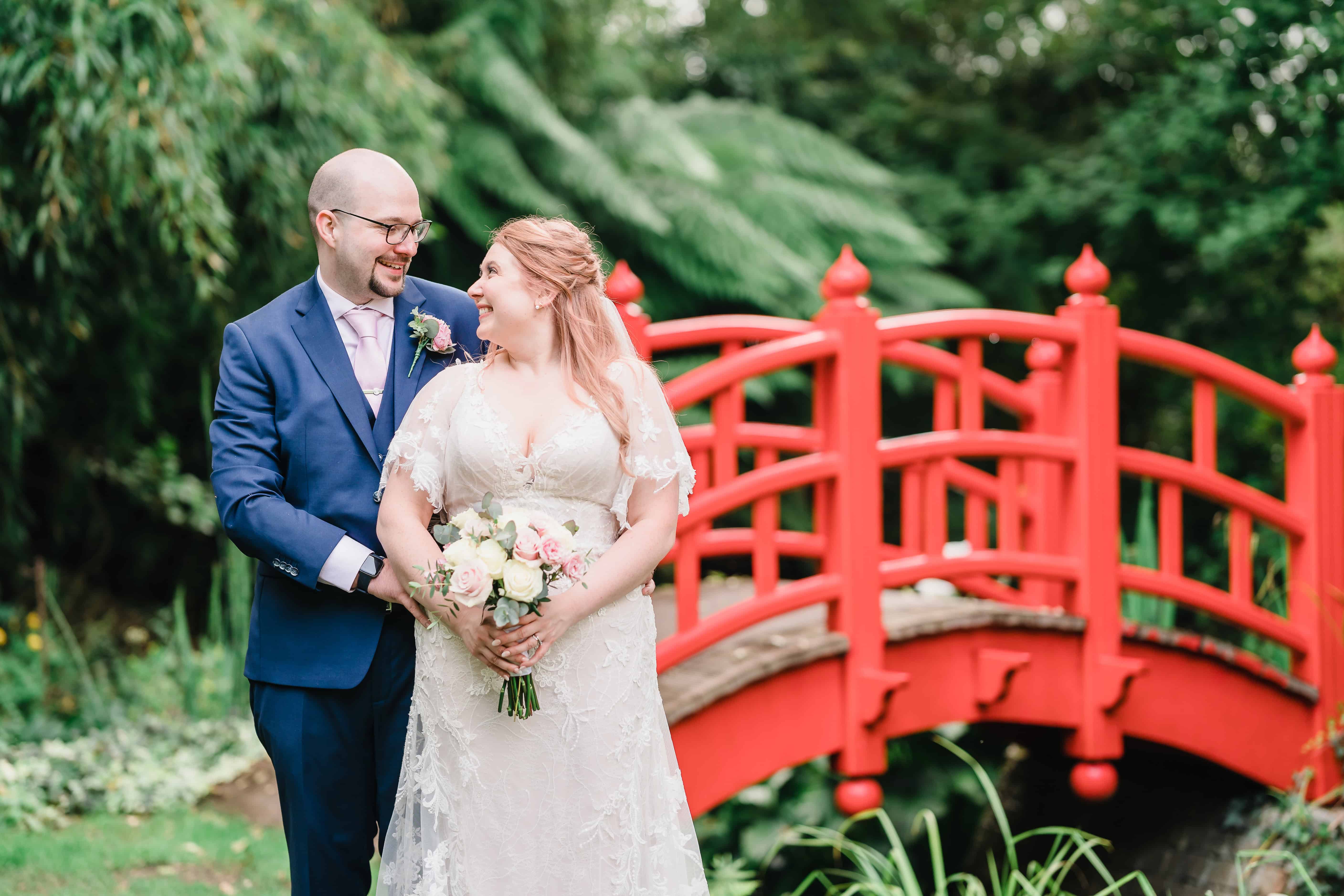 a bride and groom in front of a red bridge by birmingham wedding photographer Paul Phipps-williams