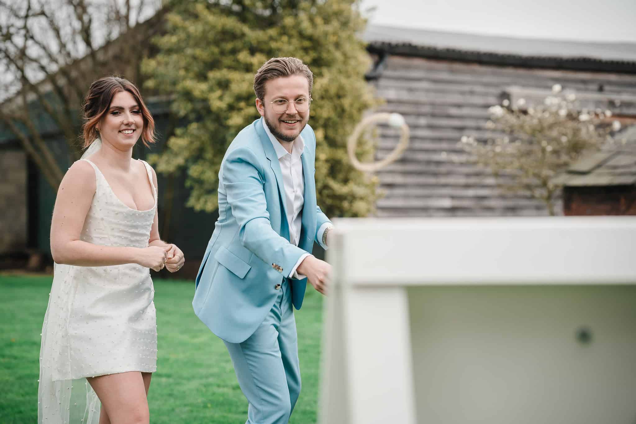 Happy wedding couple enjoying outdoor game in garden setting.