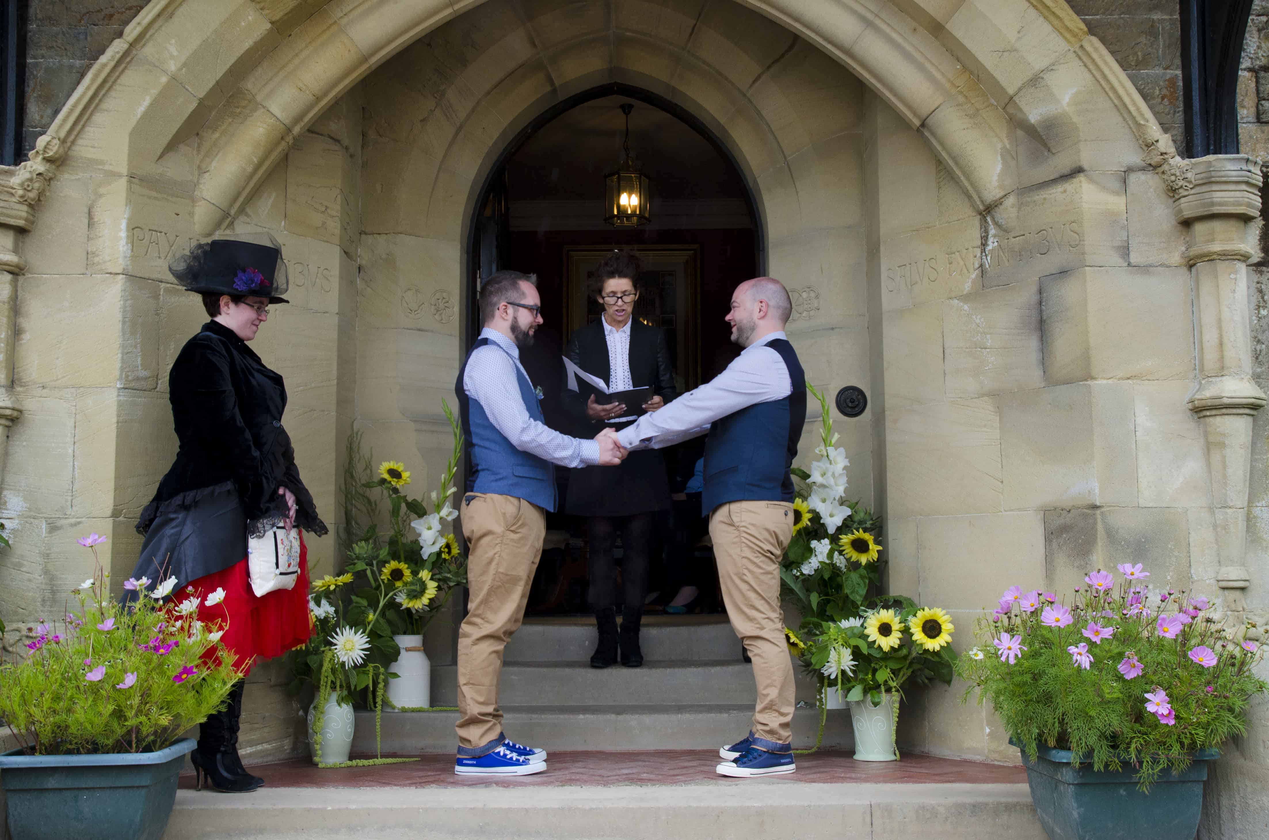two men get married under the arch of a country house