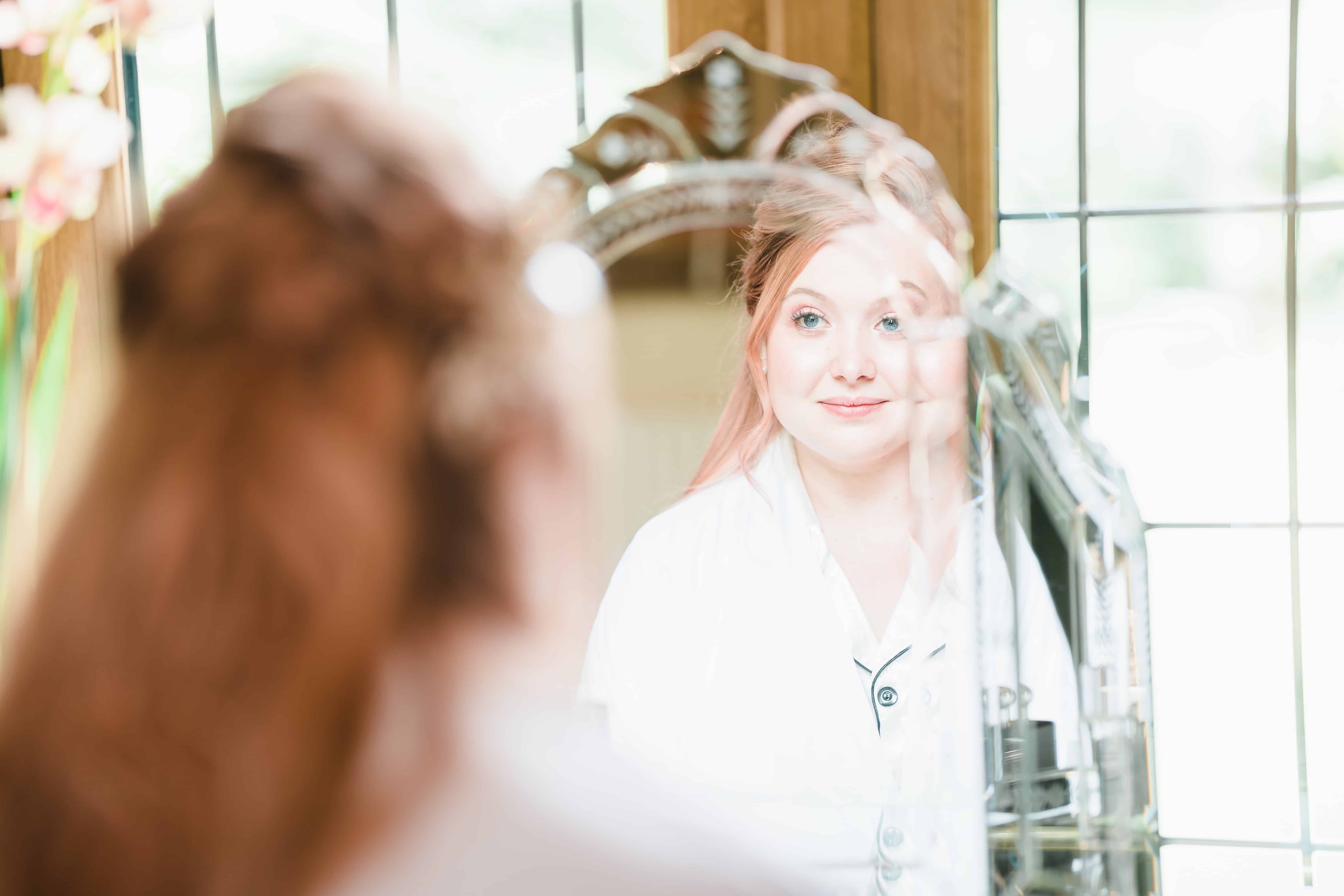 a bride gets ready in the mirror at Rivervale Barn
