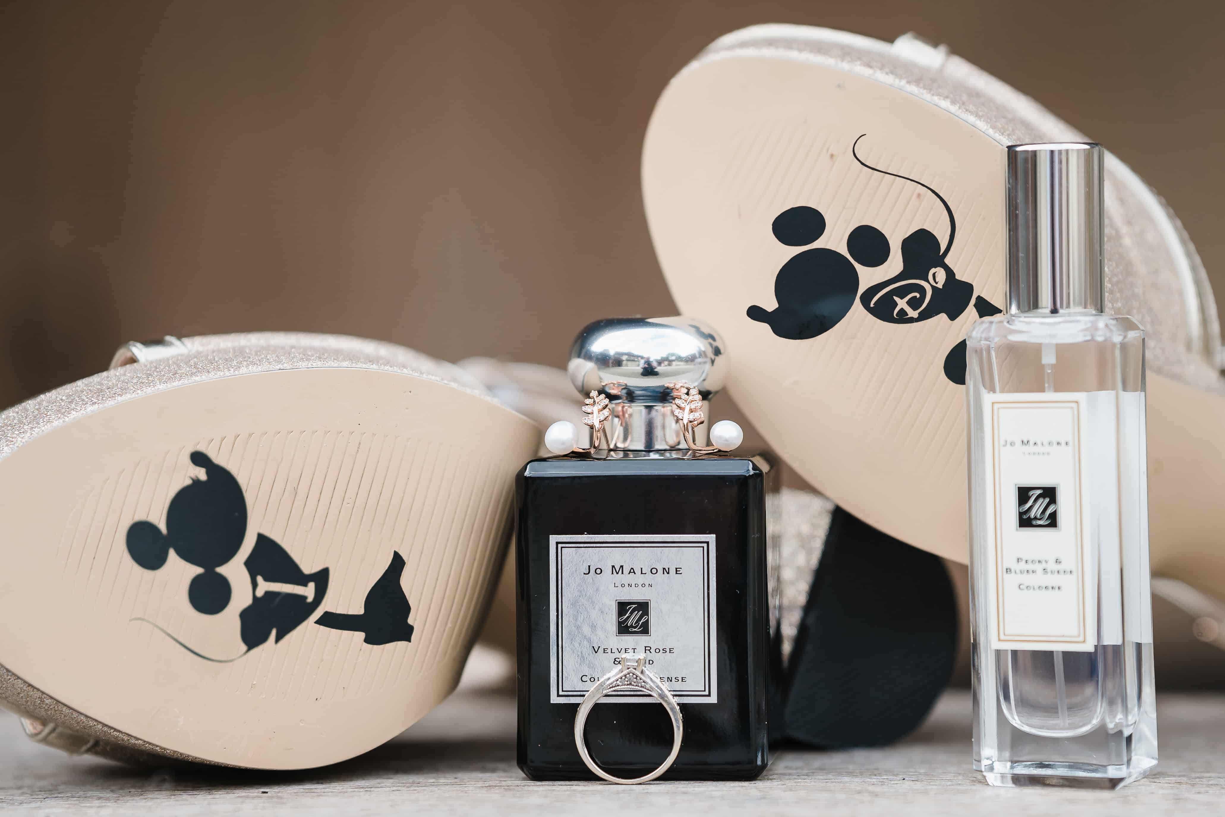 wedding shoes with Micky and Minnie Mouse on the bottom and the words "I Do" with wedding rings and perfume bottles