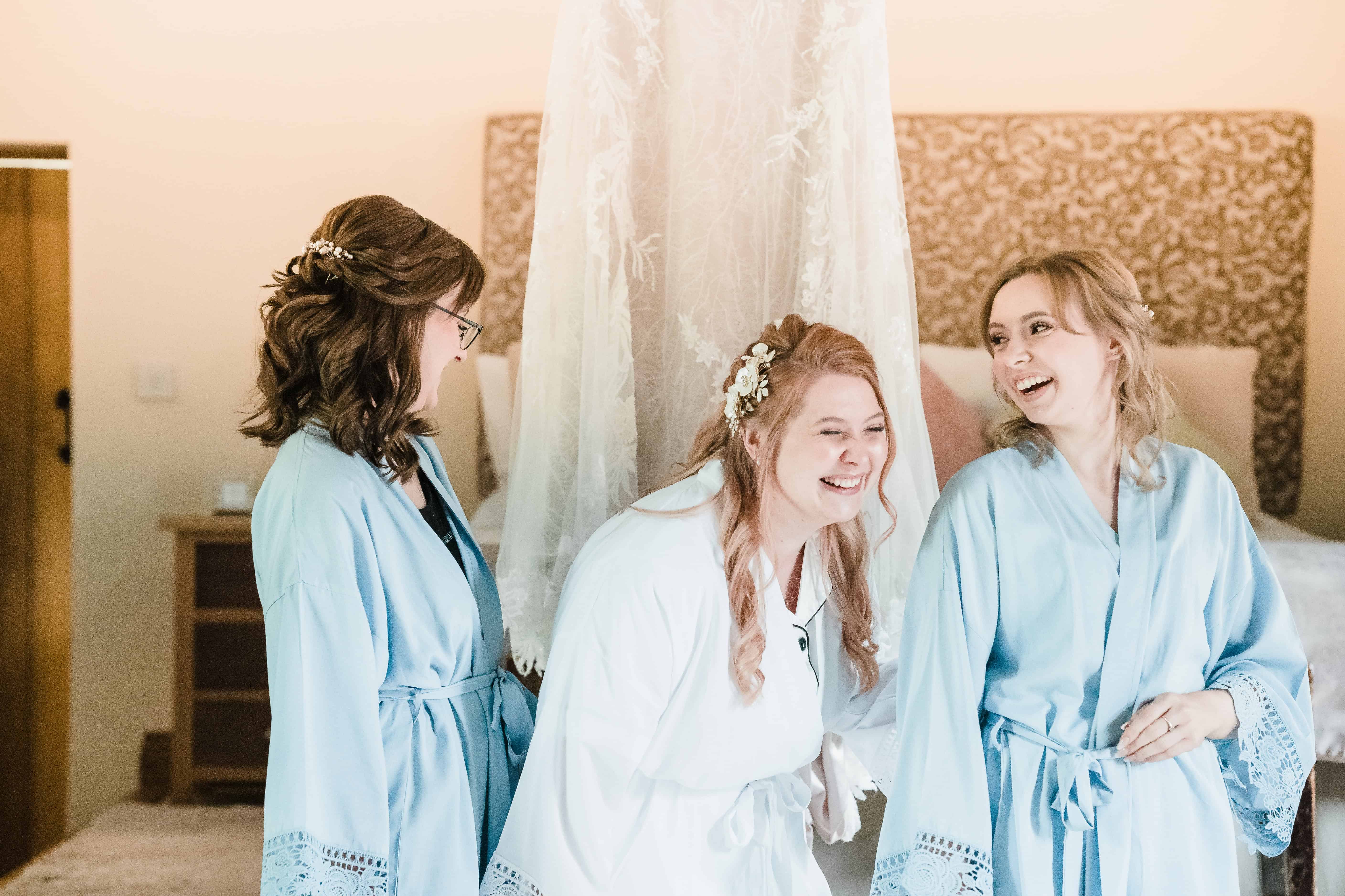 bride and wedding party laugh in the prep room at Rivervale Barn