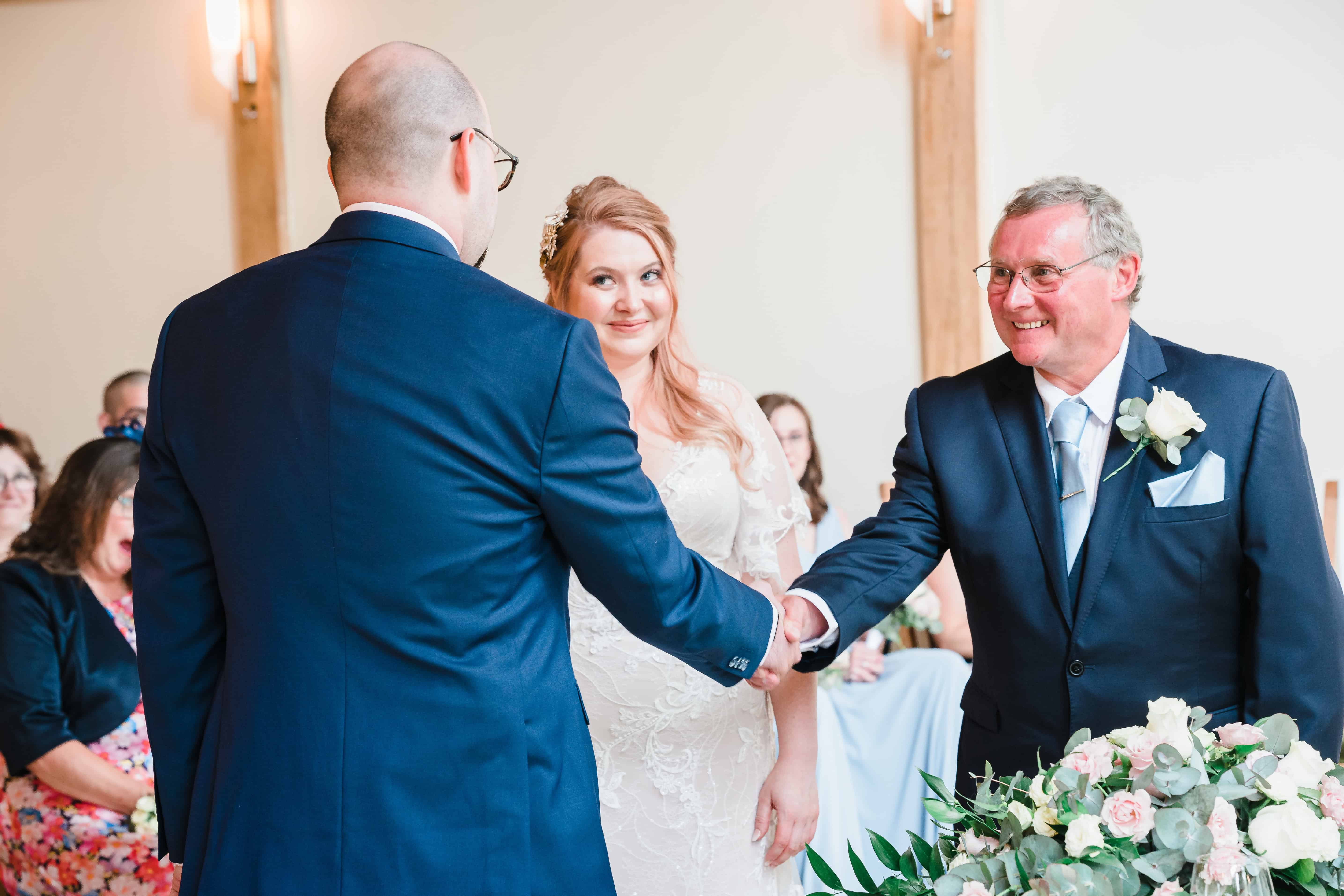 father of the bride shakes hands with a groom at barford park barn