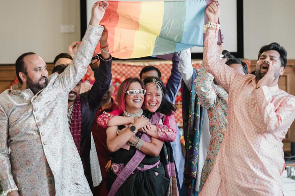 two women walk under a pride flag at their wedding
