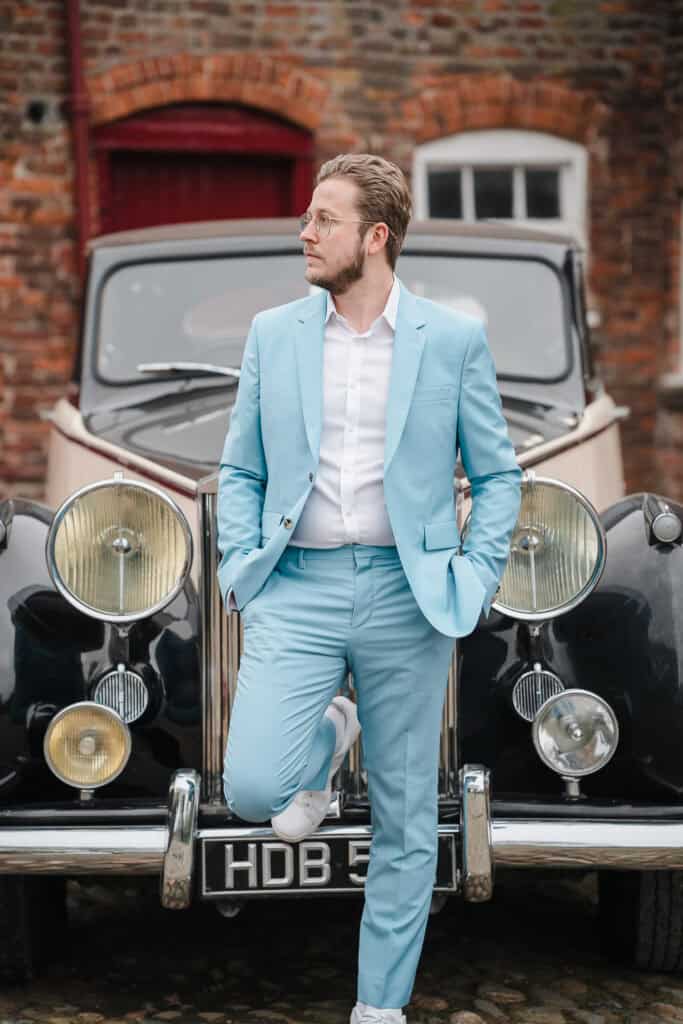 a groom in front of his classic car at a wedding