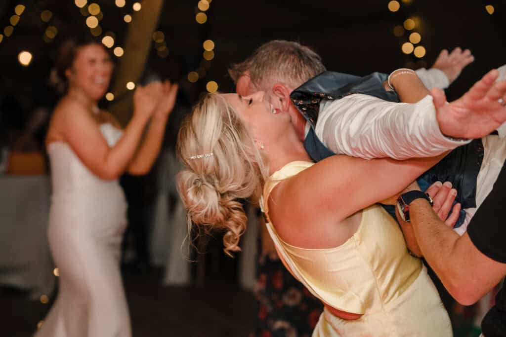 a wedding guest catches a groom on the dance floor whilst the bride laughs in the background at Newlands Bishop Farm